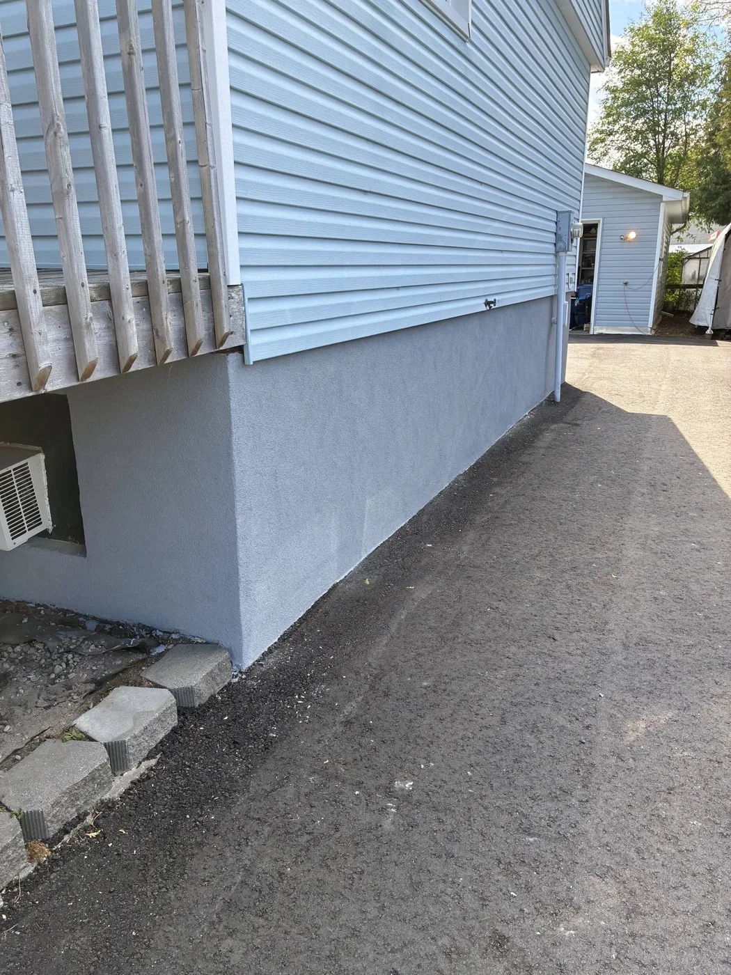 Smooth grey parged foundation wall finished by Near North Construction and Stucco on a North Bay home